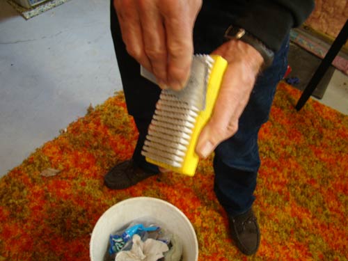Scrape the wax scraper across the wx brush bristles