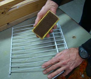 Scrape brush across wire shelf